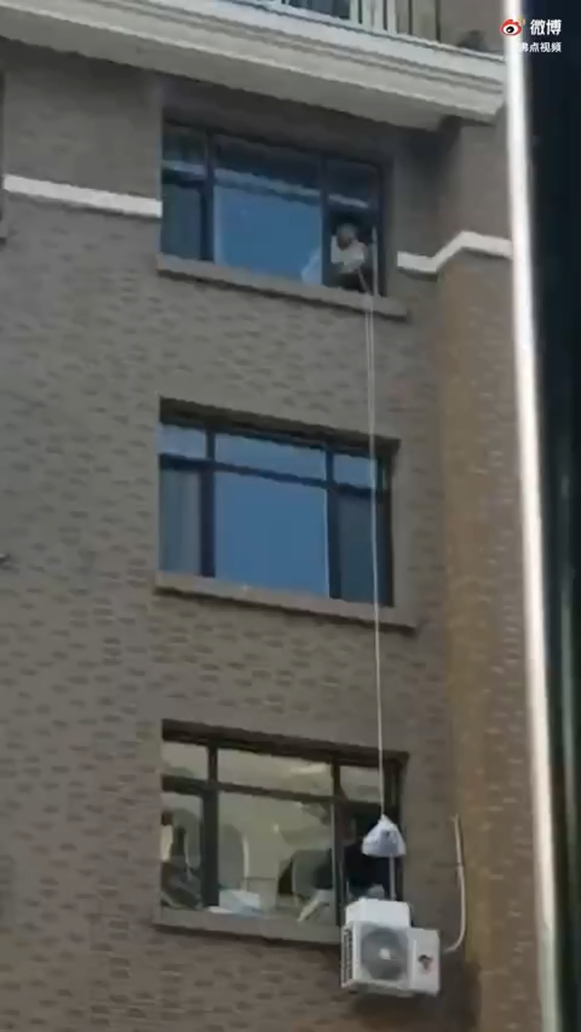 網傳通化市有居民以吊繩將物資輸送給樓上住戶。(影片截圖) 網傳通化市有居民以吊繩將物資輸送給樓上住戶。(影片截圖)