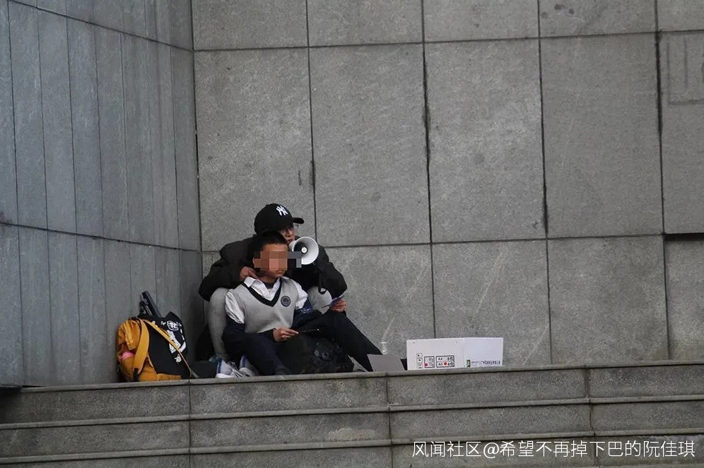王某某挾持一名男學生，蹲在校門外一側角落與警方對峙。（網上圖片）