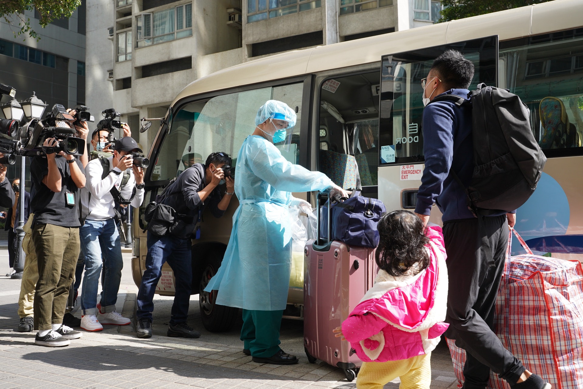 疑似密切接觸者的一家三口從五座步出,並帶著行李箱上旅遊巴離開。(鄭子峰攝) 疑似密切接觸者的一家三口從五座步出,並帶著行李箱上旅遊巴離開。(鄭子峰攝)