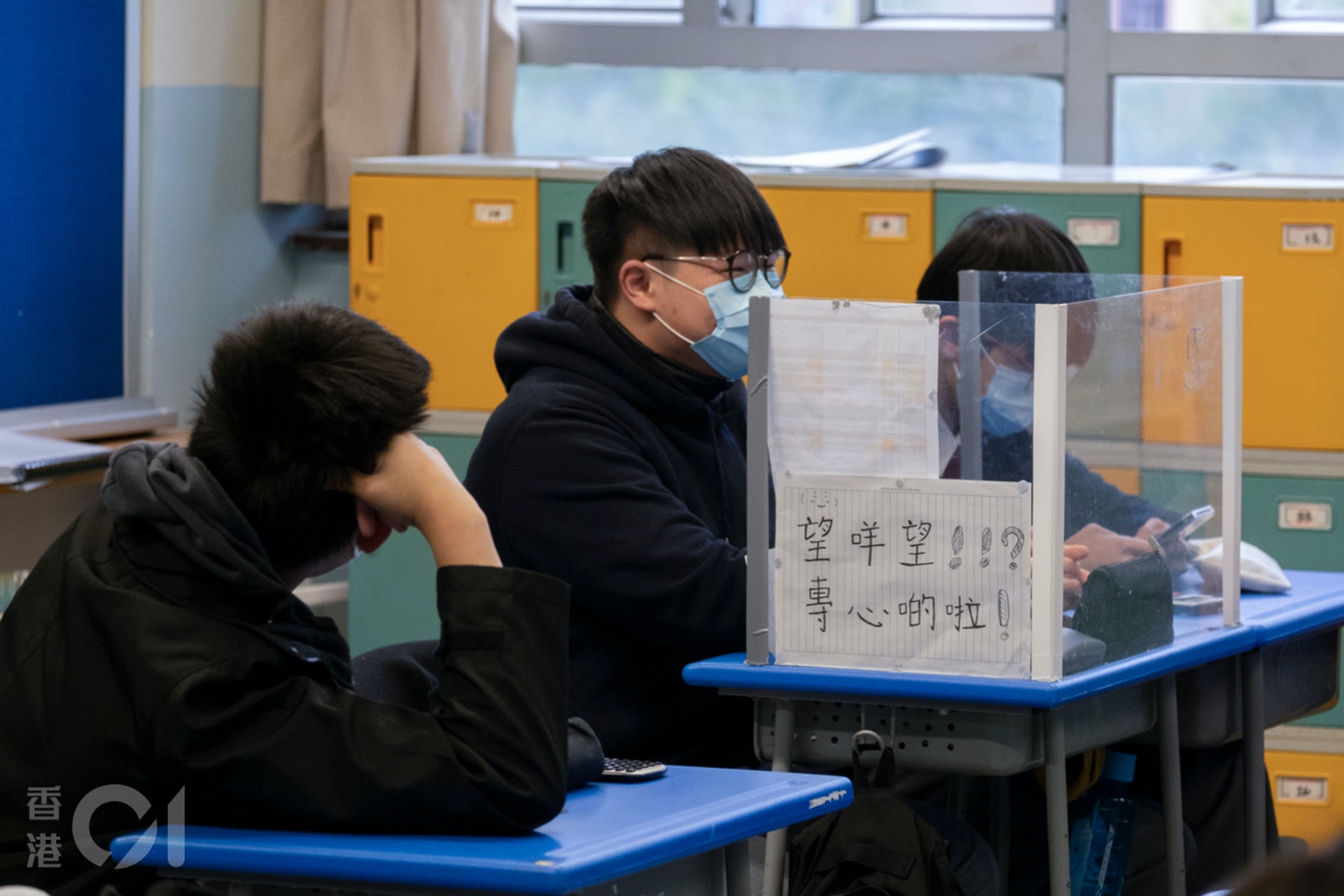 1月11日,教育局容許中小學安排不多於全校六分之一學生回校,恢復面授課堂。有學生在防疫膠板貼上「告示」,提醒同學專心上課。(梁鵬威攝) 1月11日,教育局容許中小學安排不多於全校六分之一學生回校,恢復面授課堂。有學生在防疫膠板貼上「告示」,提醒同學專心上課。(梁鵬威攝)