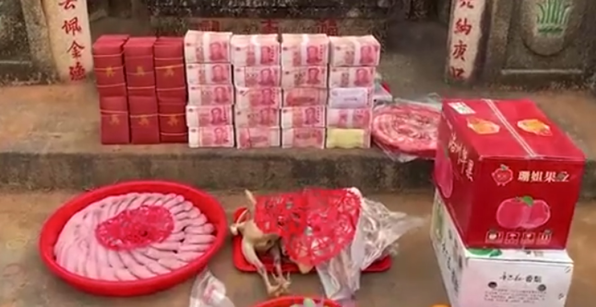 除了一般的祭品如牲畜、水果及糕點外,片中亦見到墳前放有價值至少數十萬元的百元面額人民幣現鈔。(微博片段截圖) 除了一般的祭品如牲畜、水果及糕點外,片中亦見到墳前放有價值至少數十萬元的百元面額人民幣現鈔。(微博片段截圖)