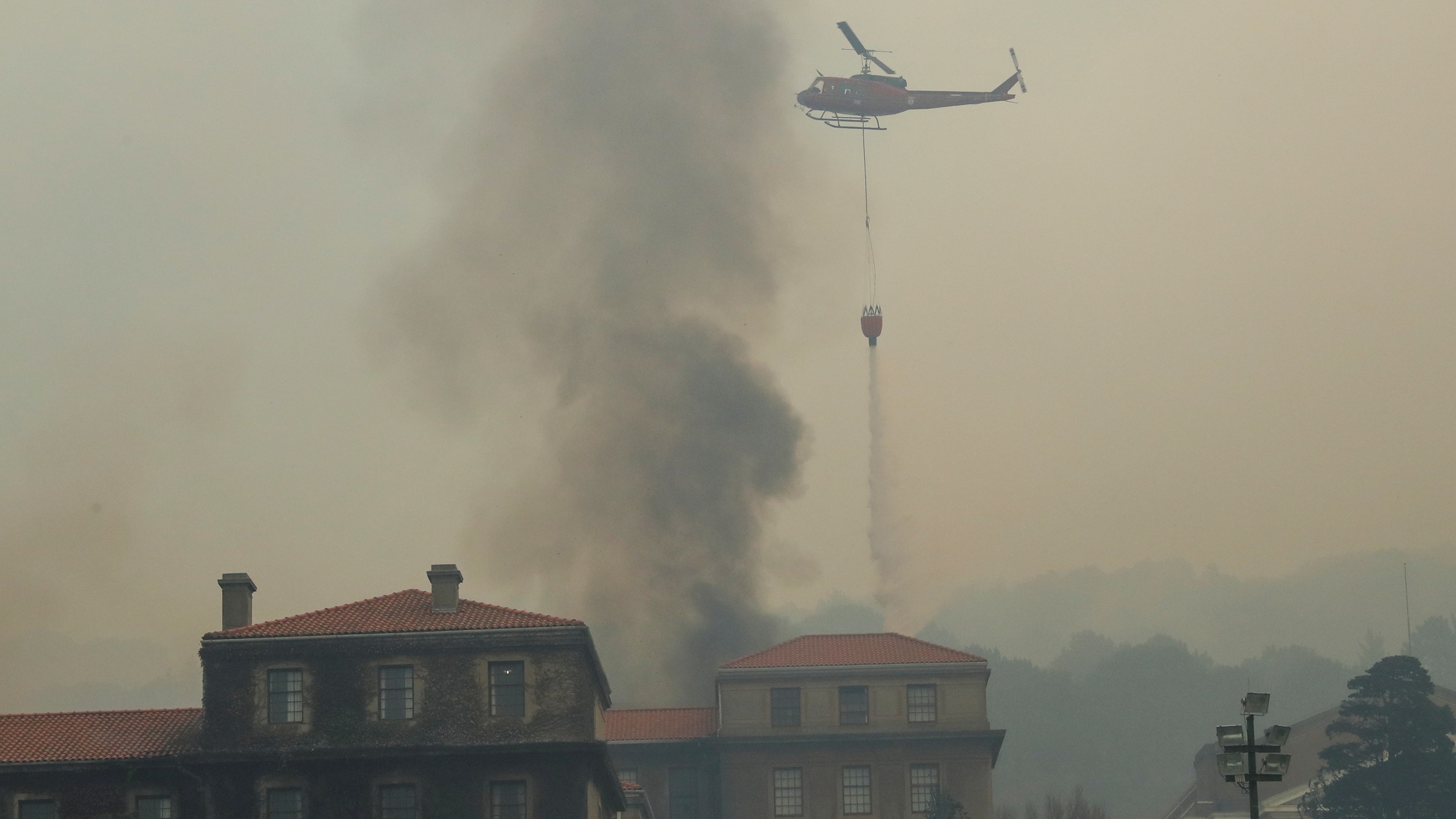 桌山山火：图为4月18日，南非开普敦桌山发生山火，火势蔓延至开普敦大学图书馆，直升机投下水弹。 （Reuters）