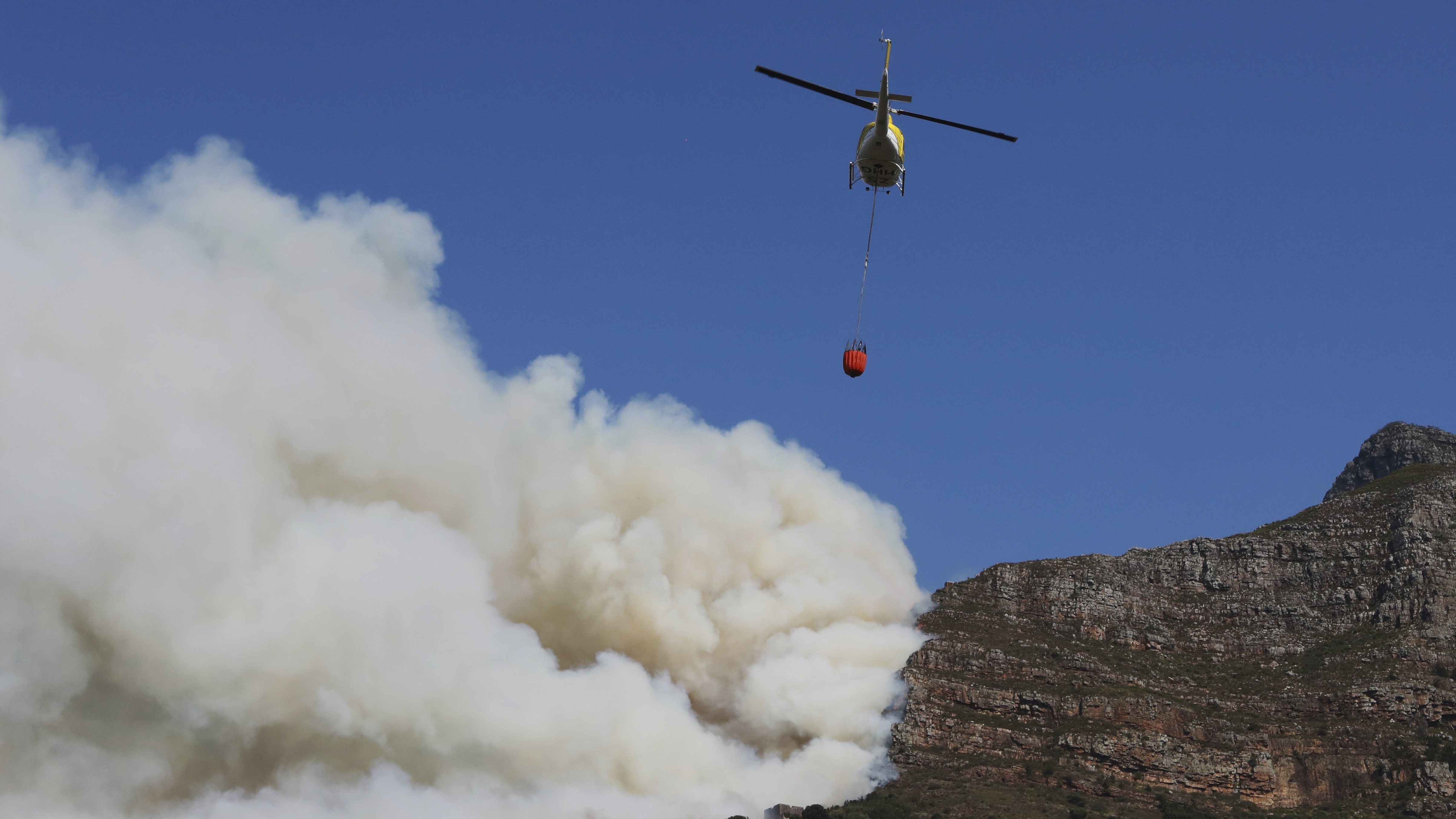 桌山山火：图为4月18日，南非开普敦桌山发生山火，直升机向桌山上的投下水弹。 （AP）