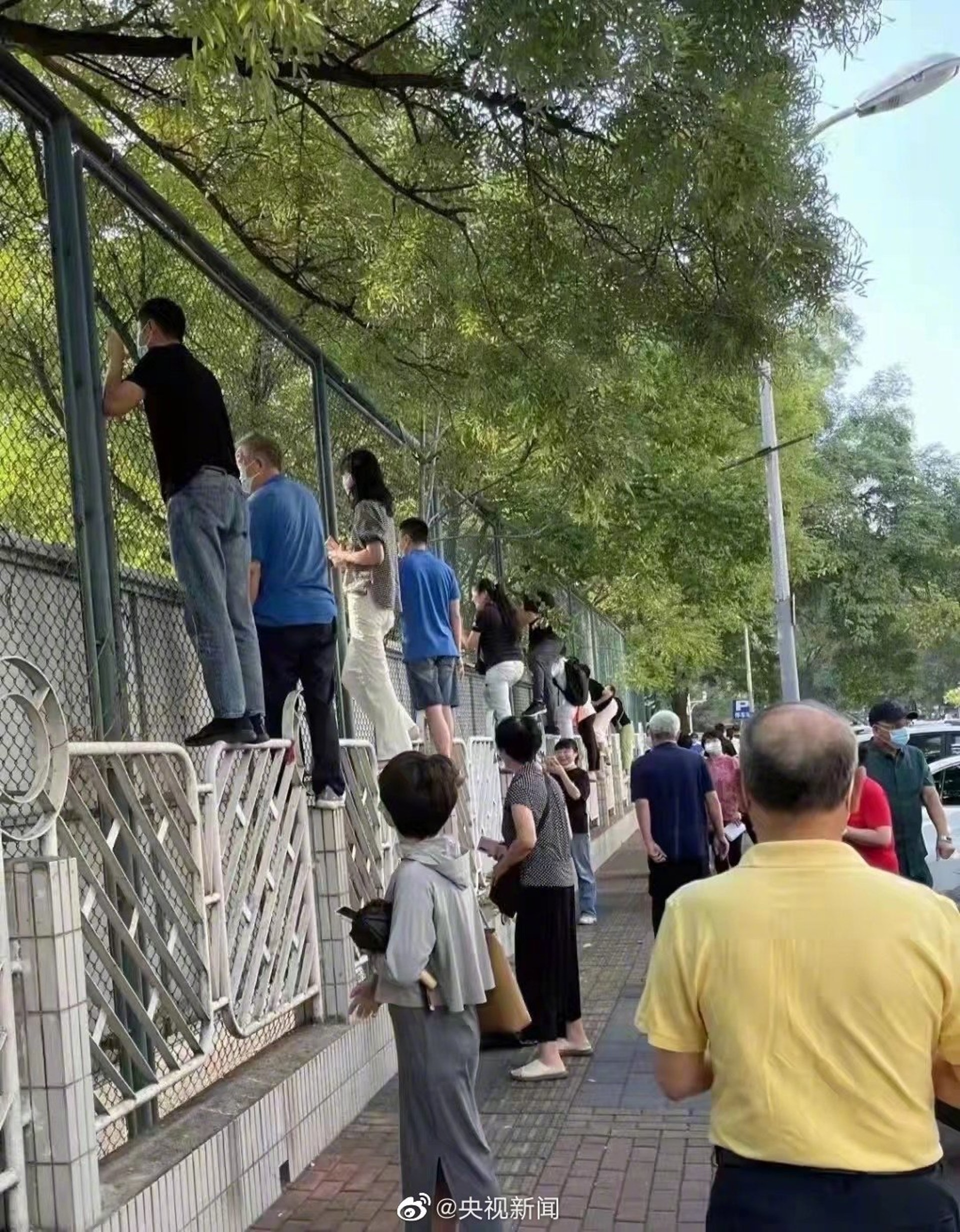 有家長攀爬上學校外的欄杆。(央視新聞) 有家長攀爬上學校外的欄杆。(央視新聞)
