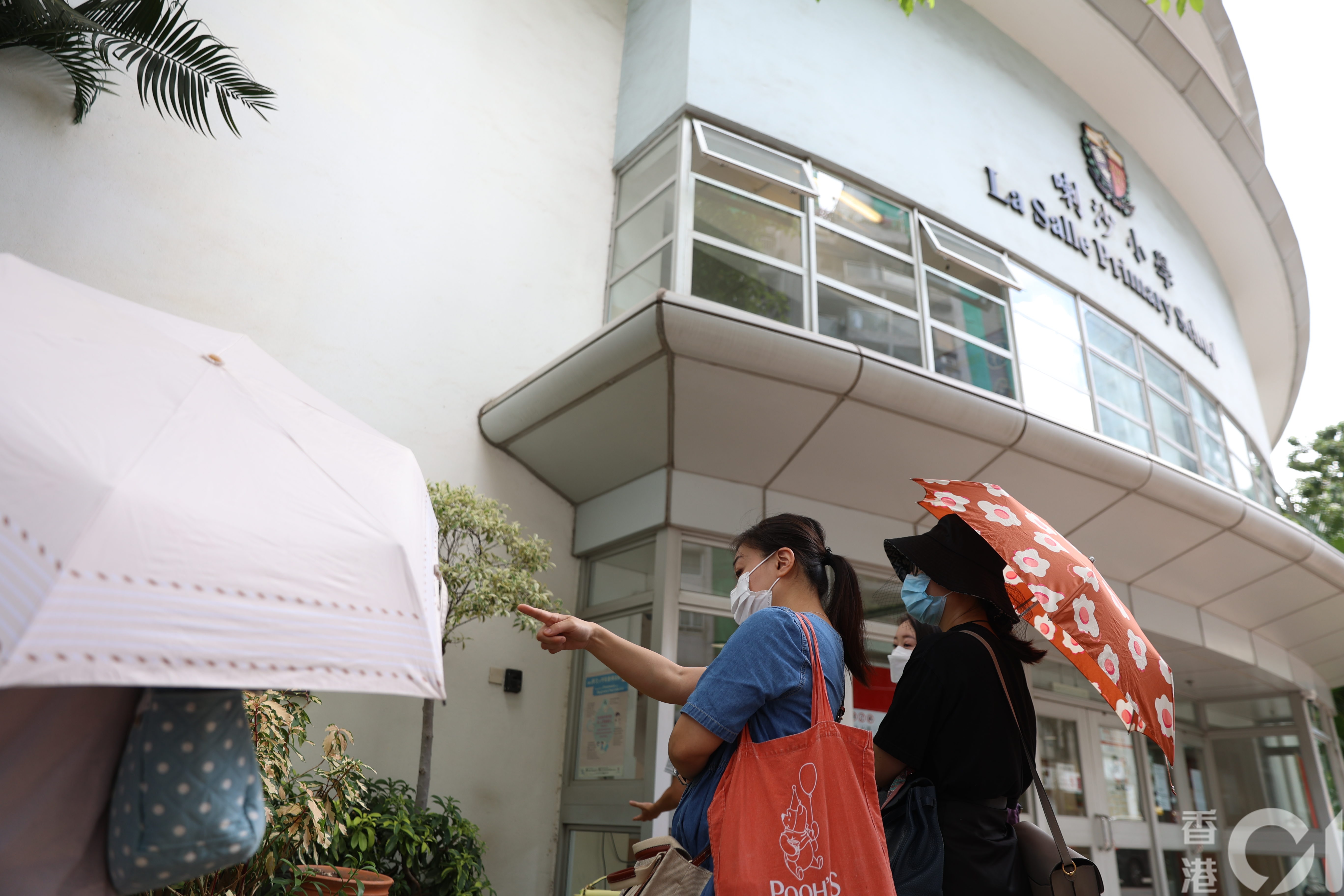 喇沙小學今早9時才開始收表，此前已有約20名家長於校門外排隊等候。 （鄭子峰攝）