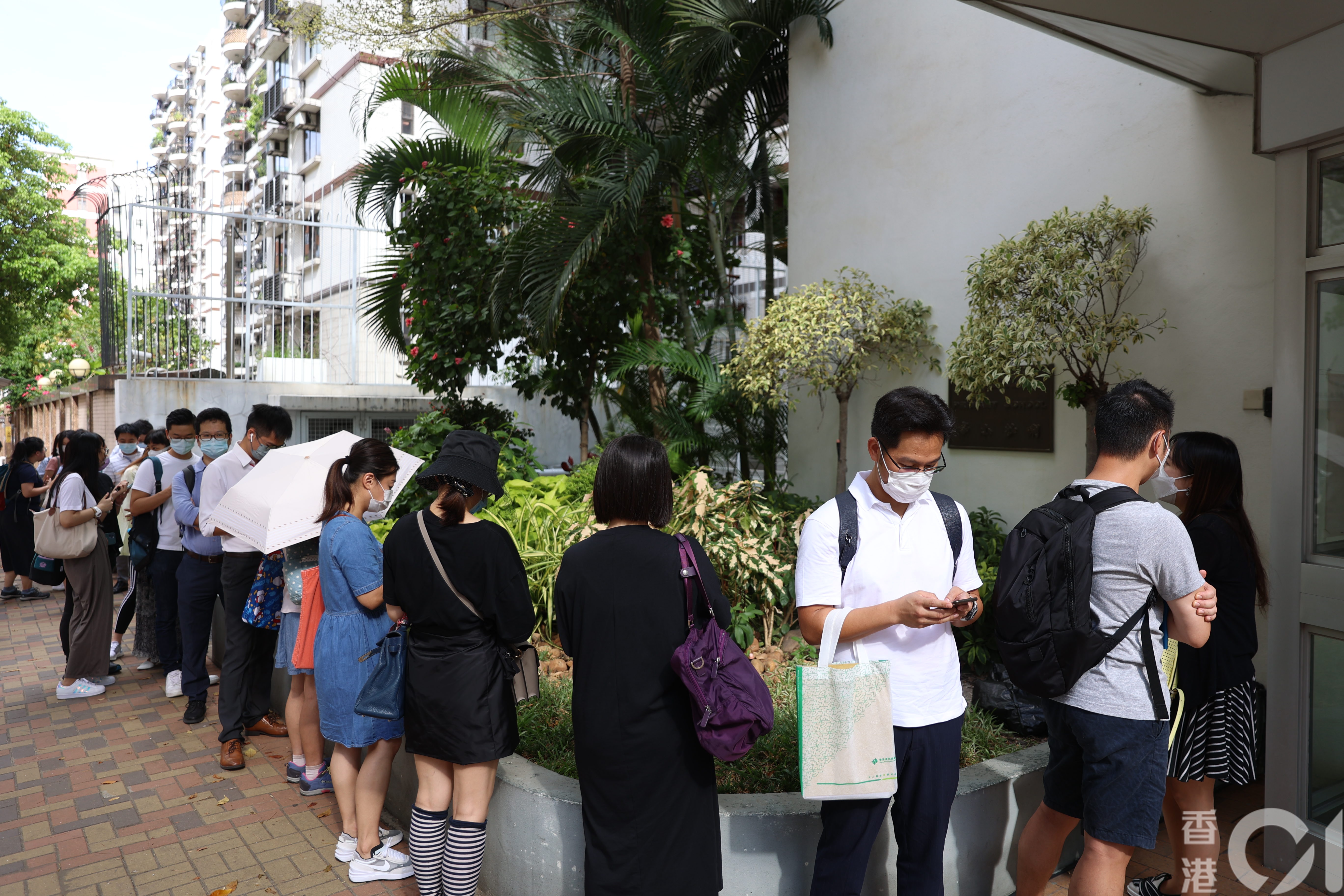 喇沙小學今早9時才開始收表，此前已有約20名家長於校門外排隊等候。 （鄭子峰攝）