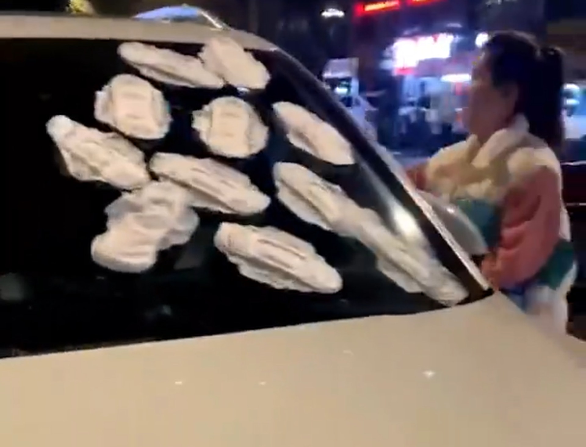 女子等了足足3小時,忍無可忍之下到了附近的便利店,購入2至3包衛生巾,在白色保時捷的擋風玻璃及兩側車窗上狂貼泄忿。(微博影片截圖)
