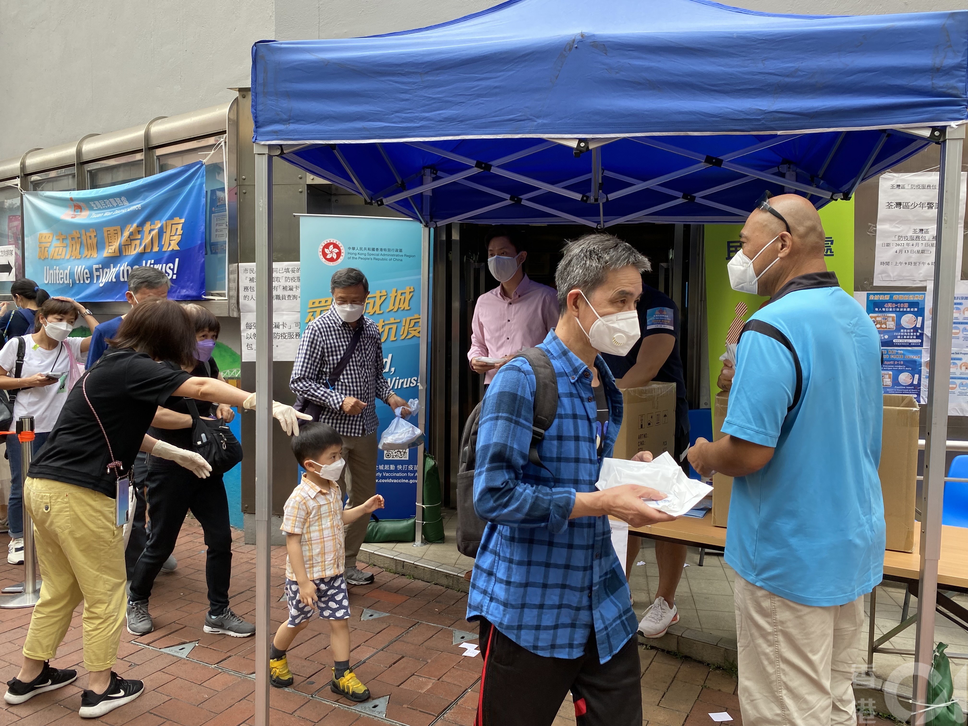 防疫服務包派發至4月13日結束，在荃灣一個補發站，工作人員向每位排隊市民送上四包快速抗原測試包。(倪清江攝）