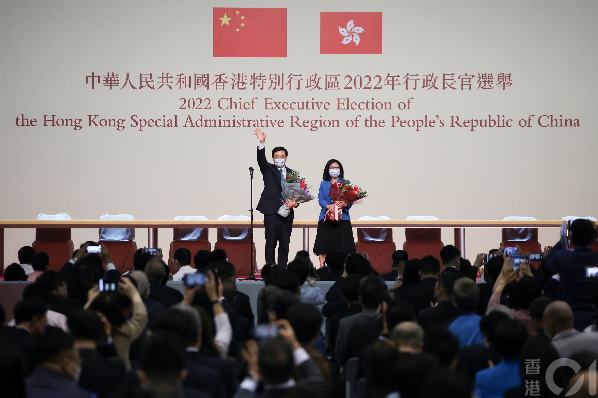 李家超伉儷在台上手持花束向台下致意。（李澤彤攝）