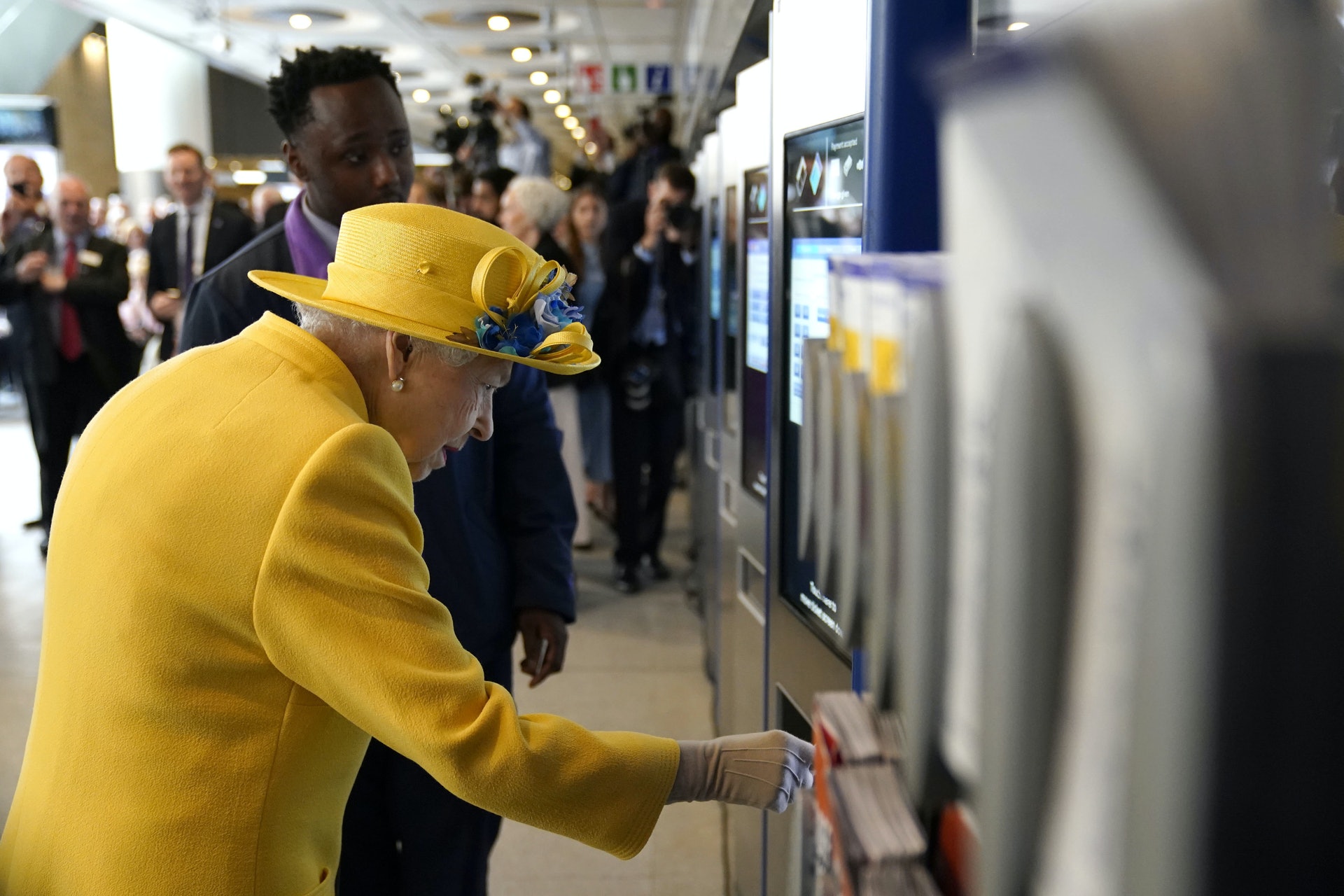 英女王伊利沙伯二世5月17日到訪倫敦帕丁頓車站,為以她命名的鐵路新線「伊利沙伯線」舉行揭幕儀式,期間有車站職員向她講解如何使用售票機。(AP) 英女王伊利沙伯二世5月17日到訪倫敦帕丁頓車站,為以她命名的鐵路新線「伊利沙伯線」舉行揭幕儀式,期間有車站職員向她講解如何使用售票機。(AP)