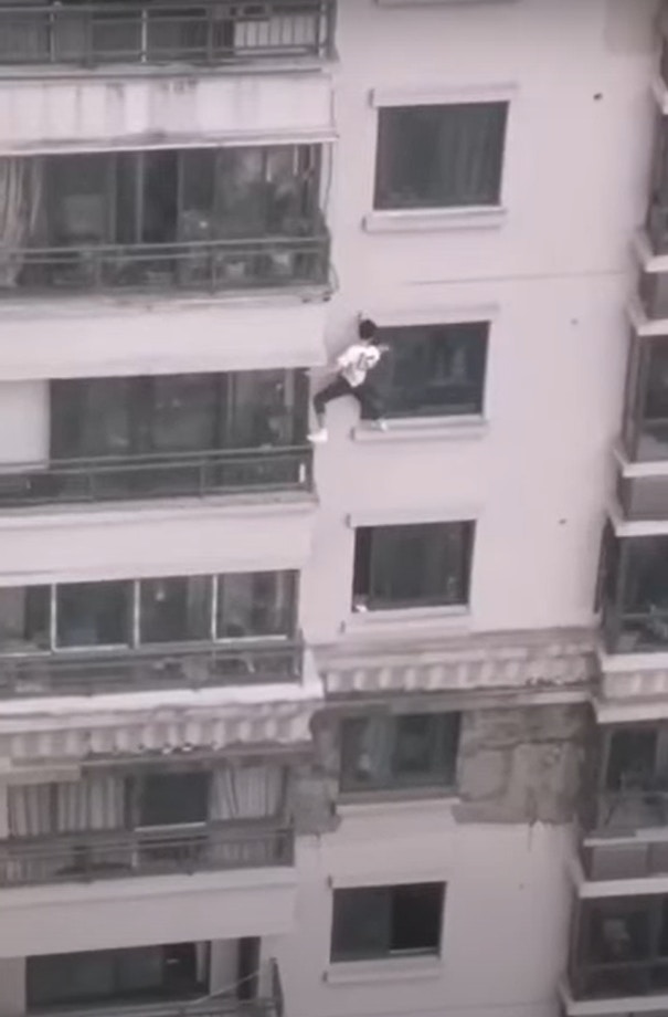 內地網絡瘋傳影片，1名穿白衣男子在37層樓高的大樓外牆徒手攀爬，一路向下爬至3樓才獲救，現場畫面驚險萬分。（短片截圖）