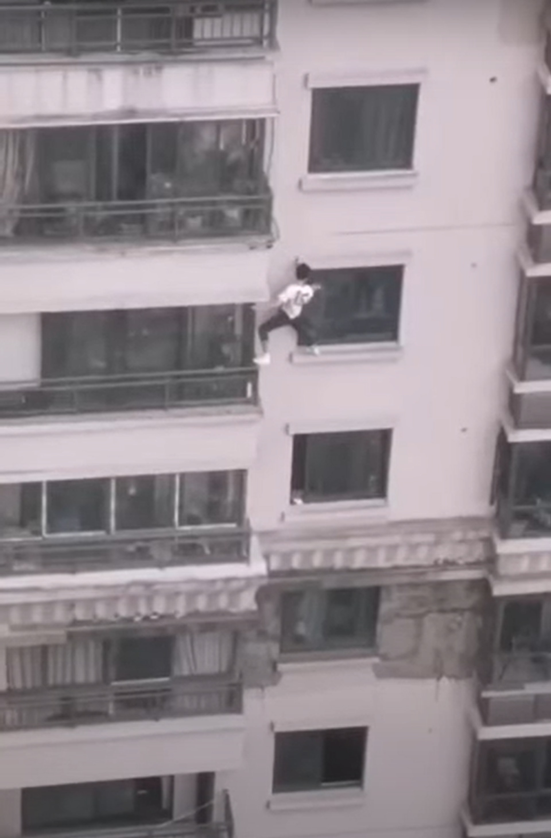 內地網絡瘋傳影片,1名穿白衣男子在37層樓高的大樓外牆徒手攀爬,一路向下爬至3樓才獲救,現場畫面驚險萬分。(短片截圖) 內地網絡瘋傳影片,1名穿白衣男子在37層樓高的大樓外牆徒手攀爬,一路向下爬至3樓才獲救,現場畫面驚險萬分。(短片截圖)