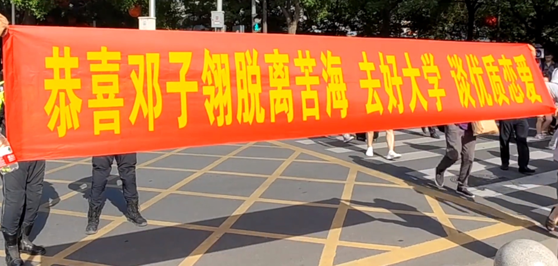 內地1名爸爸為慶祝女兒完成高考,竟在考場外拉起橫額,上面不但寫有女兒全名,更明目張膽催促她談戀愛,令女兒驚喜又尷尬。(微博影片截圖) 內地1名爸爸為慶祝女兒完成高考,竟在考場外拉起橫額,上面不但寫有女兒全名,更明目張膽催促她談戀愛,令女兒驚喜又尷尬。(微博影片截圖)
