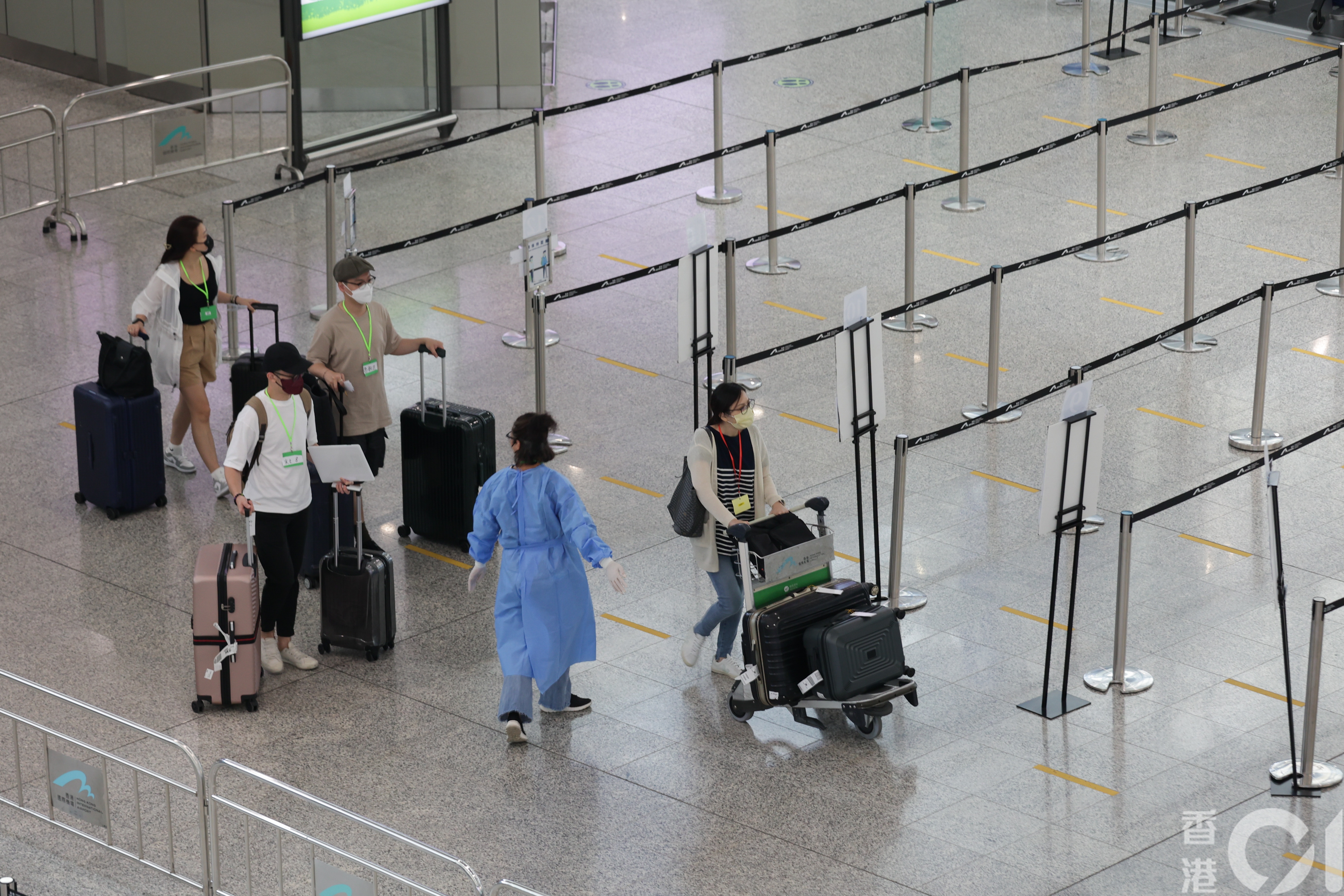 乘搭飞机返港人数在暑假日渐增多，7月25日有大批人士在抵港层，等候乘搭专车往检疫酒店。（苏炜然摄）