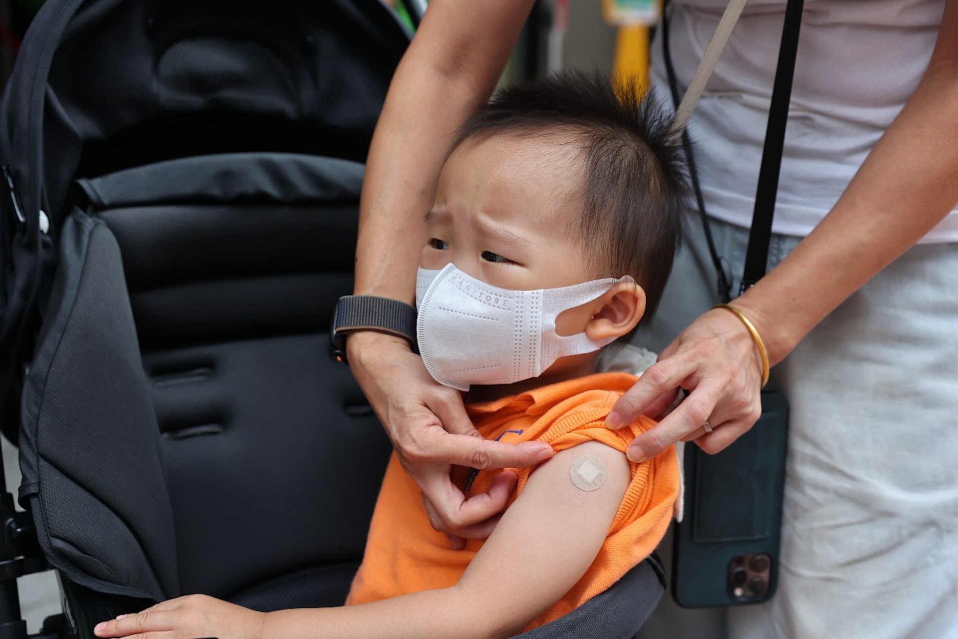 政府准許6個月至3歲的嬰幼童接種新冠疫苗後的首個星期六（8月6日），有家長帶子女到佐敦的官涌體育館疫苗中心打科興疫苗，有幼童打針後哭。（張浩維攝）