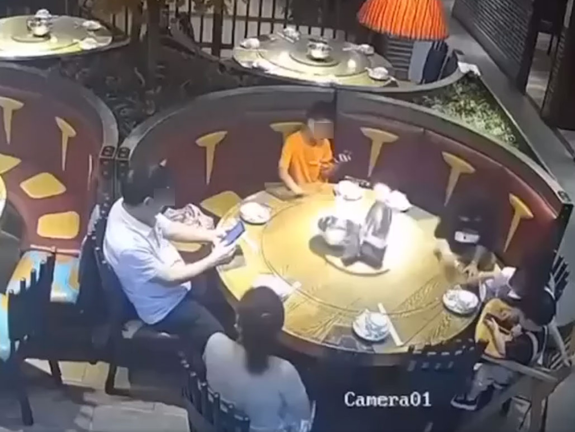 眾人等待食物期間，2名男童因貪玩不斷轉動餐枱轉盤，其中1人更是邊轉動邊玩手機。（網上片段截圖）