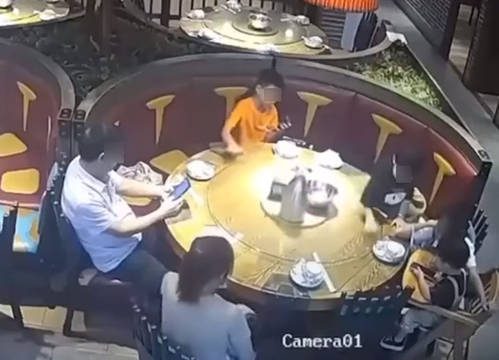 眾人等待食物期間，2名男童因貪玩不斷轉動餐枱轉盤，其中1人更是邊轉動邊玩手機。（網上片段截圖）