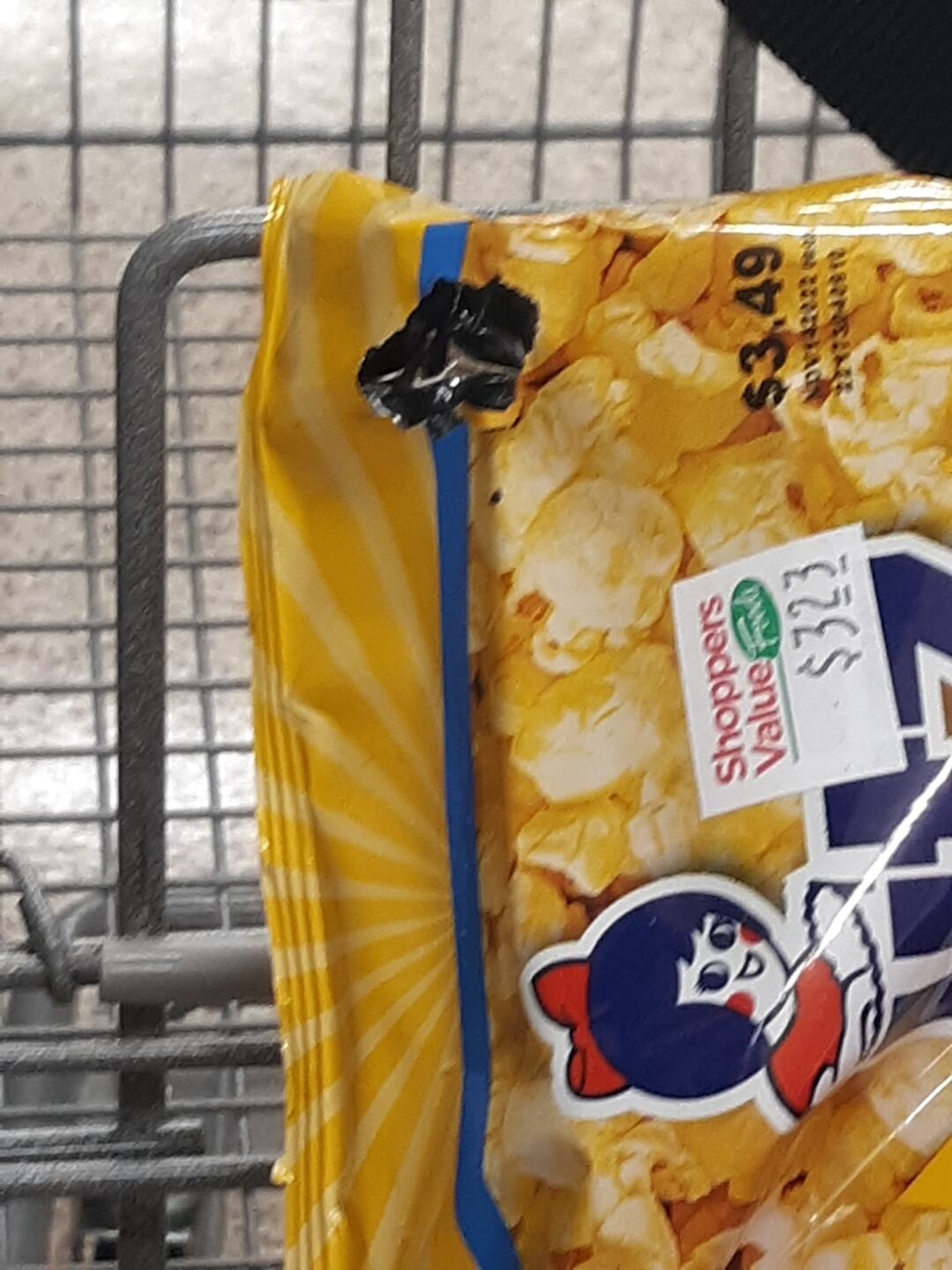 美國女子金伯利在雜貨店購買爆谷時發現一包破洞的爆谷,她把爆谷放到手推車推到櫃檯希望職員處理時,一條黑蛇突然從破洞中鑽出。(Twitter圖片) 美國女子金伯利在雜貨店購買爆谷時發現一包破洞的爆谷,她把爆谷放到手推車推到櫃檯希望職員處理時,一條黑蛇突然從破洞中鑽出。(Twitter圖片)