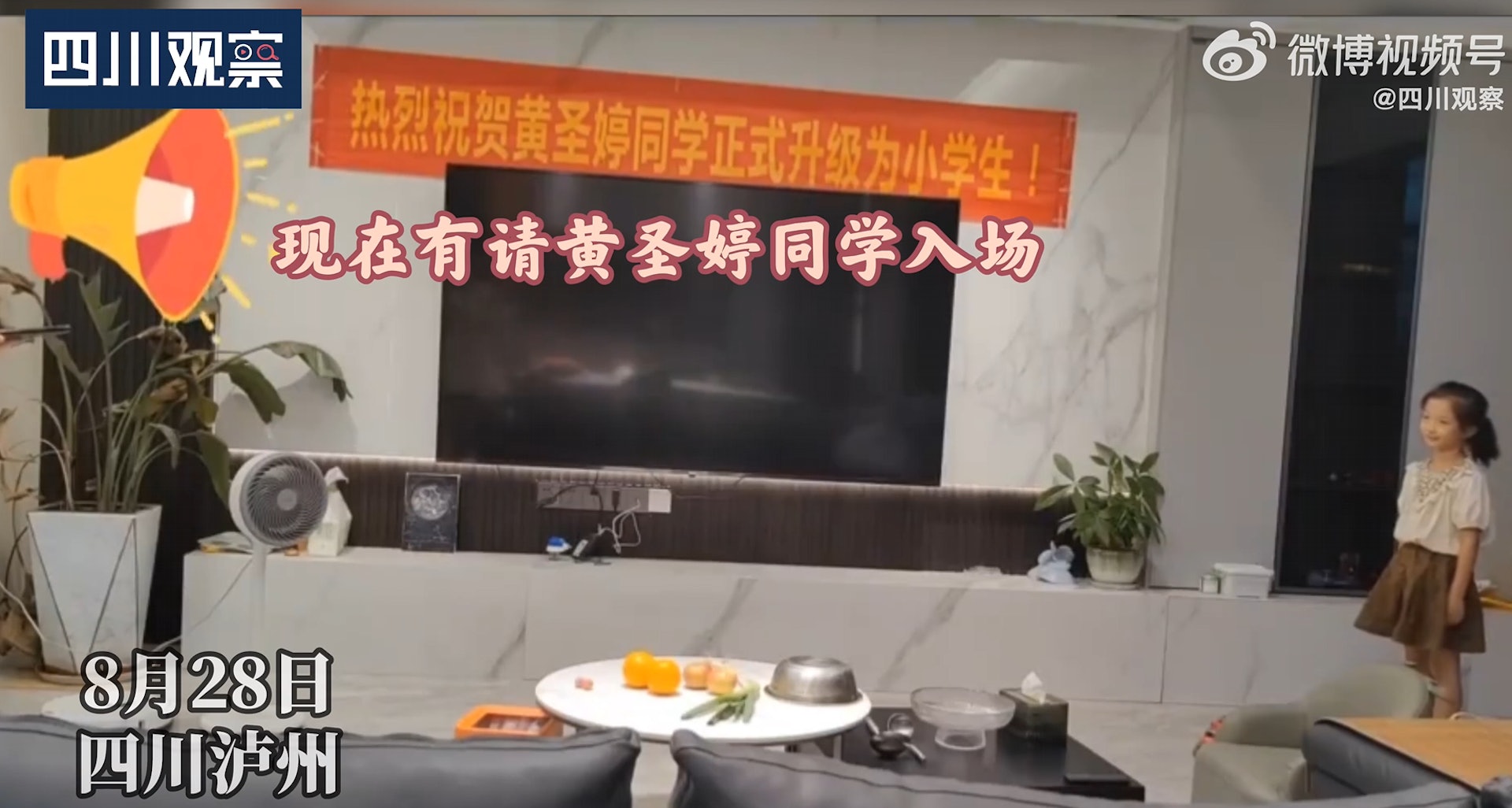 從片段可見,客廳牆壁上掛有紅底黃字的霸氣橫額,寫道「熱烈祝賀黃聖婷同學正式升級為小學生!」。(微博影片截圖) 從片段可見,客廳牆壁上掛有紅底黃字的霸氣橫額,寫道「熱烈祝賀黃聖婷同學正式升級為小學生!」。(微博影片截圖)