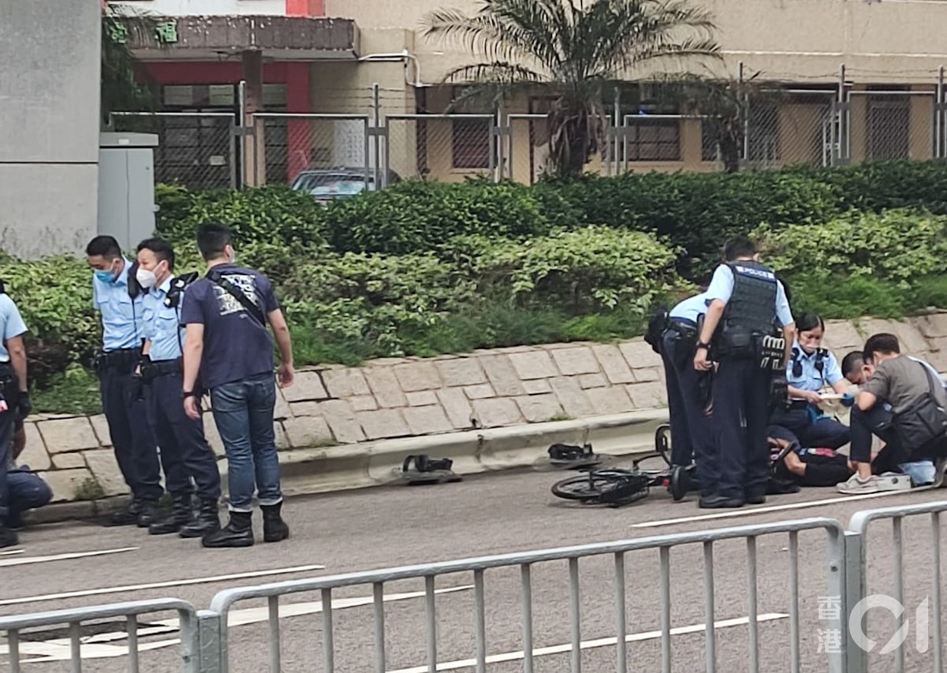 其中一名受傷男子倒臥於一輛單車旁邊,多名警員在旁協助。(讀者提供) 其中一名受傷男子倒臥於一輛單車旁邊,多名警員在旁協助。(讀者提供)