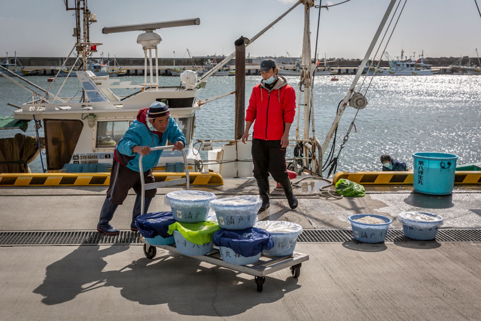 2021年3月10日，在日本福島縣浪江町，一名市場工作人員在當地已經重建的批發市場搬運魚。(Getty Images)