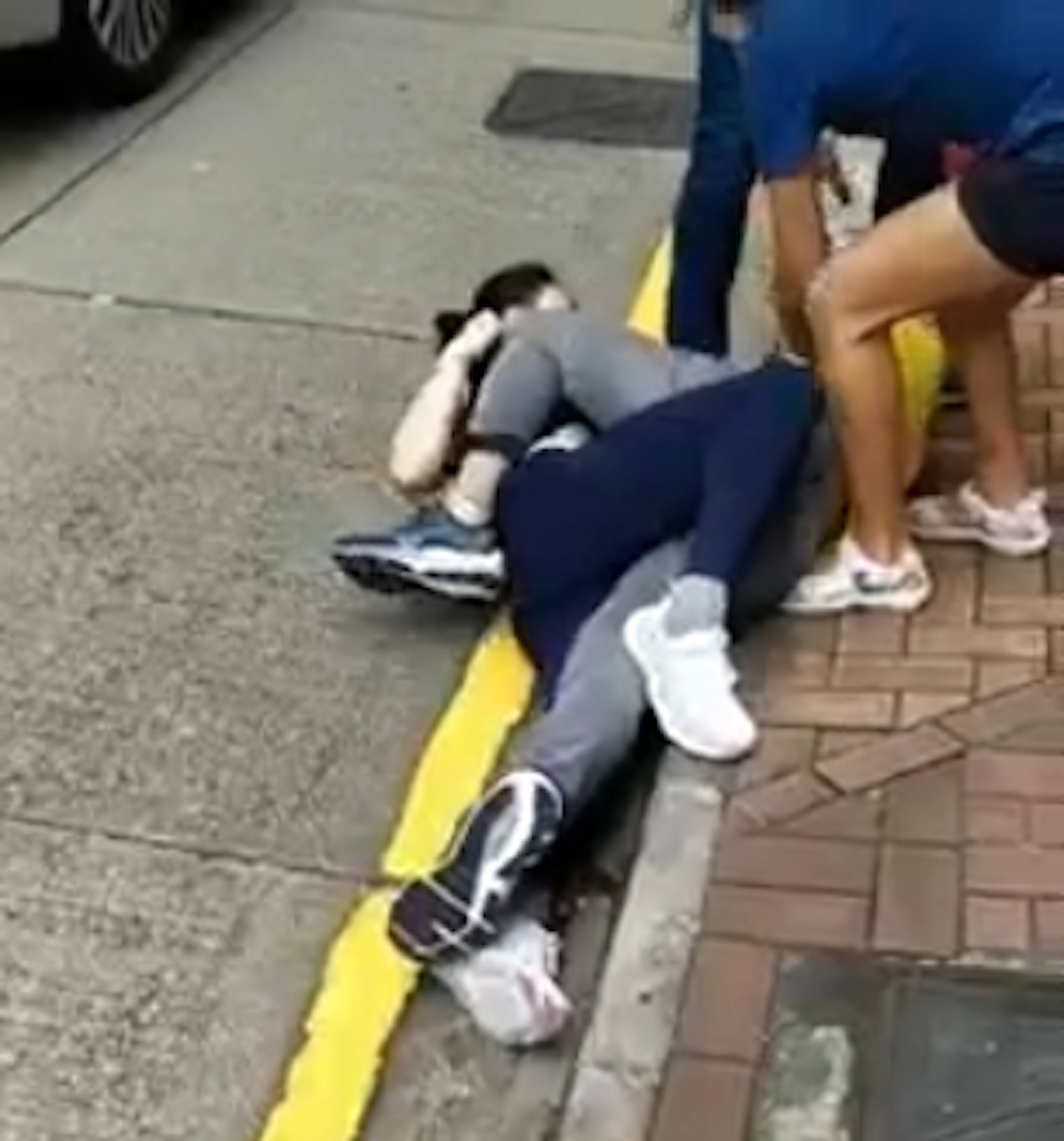2名女子在馬路邊打架，身處位置與車輛相當接近。（網上影片截圖）