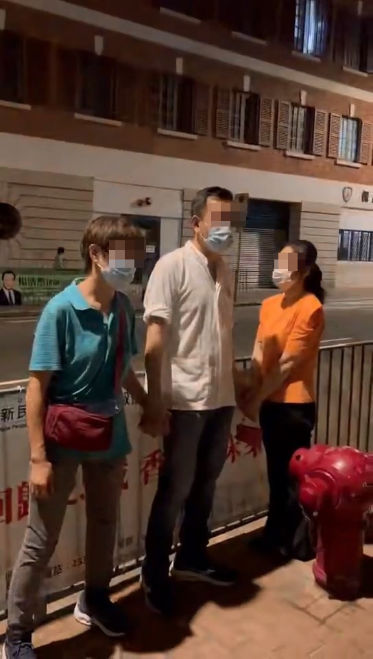 片段一開始，見到穿白色短袖上衣的男子，右手拖着一名藍衣中年婦人，左手則被較年輕的橙衣女子抓着。（Facebook群組「西環變幻時」）