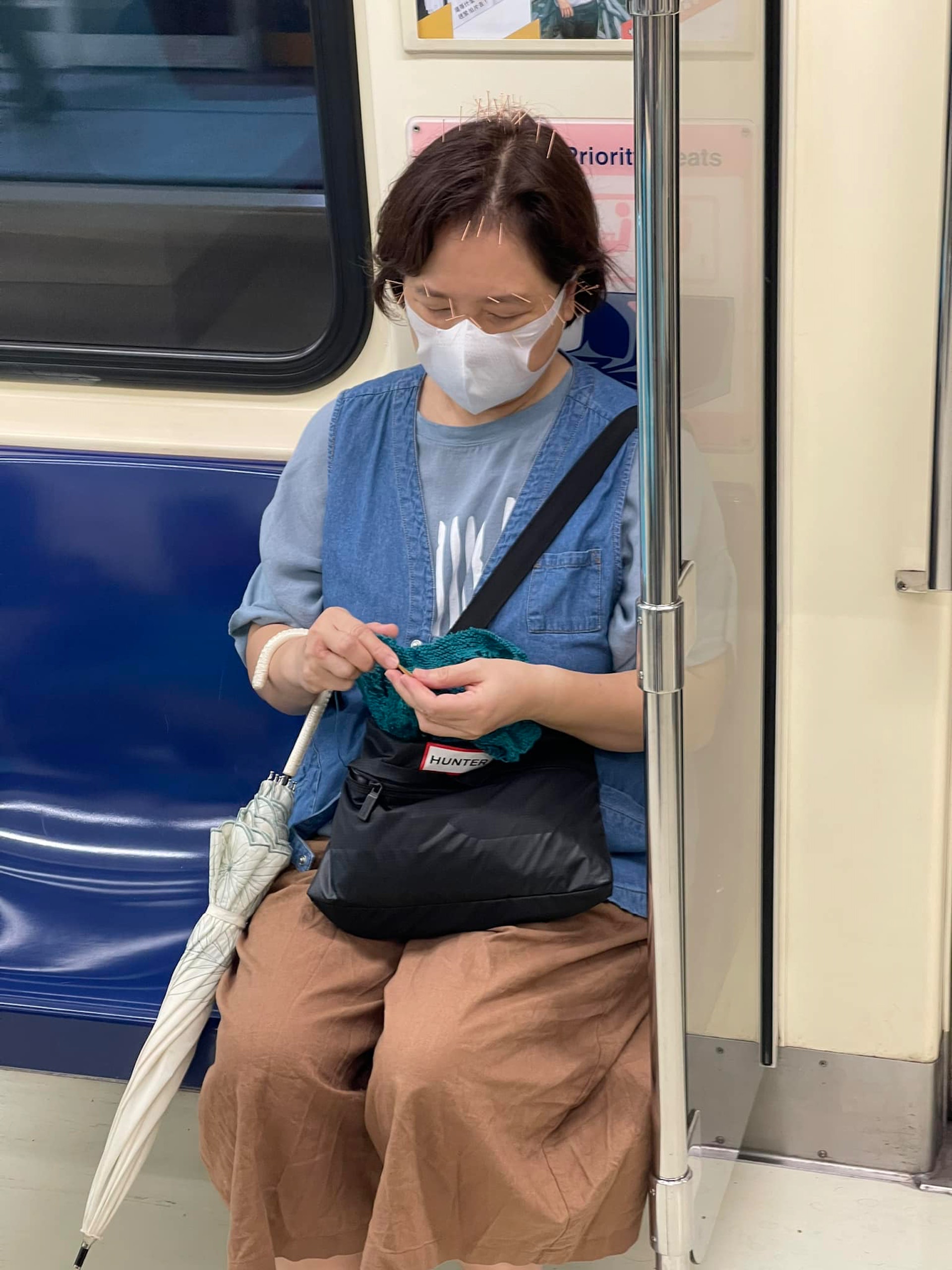 近來網上流傳一張照片，一名婦人頭上和臉上都扎滿了針，搭乘台北捷運坐在博愛座上淡定織毛衣。（Facebook / @路上觀察學院）