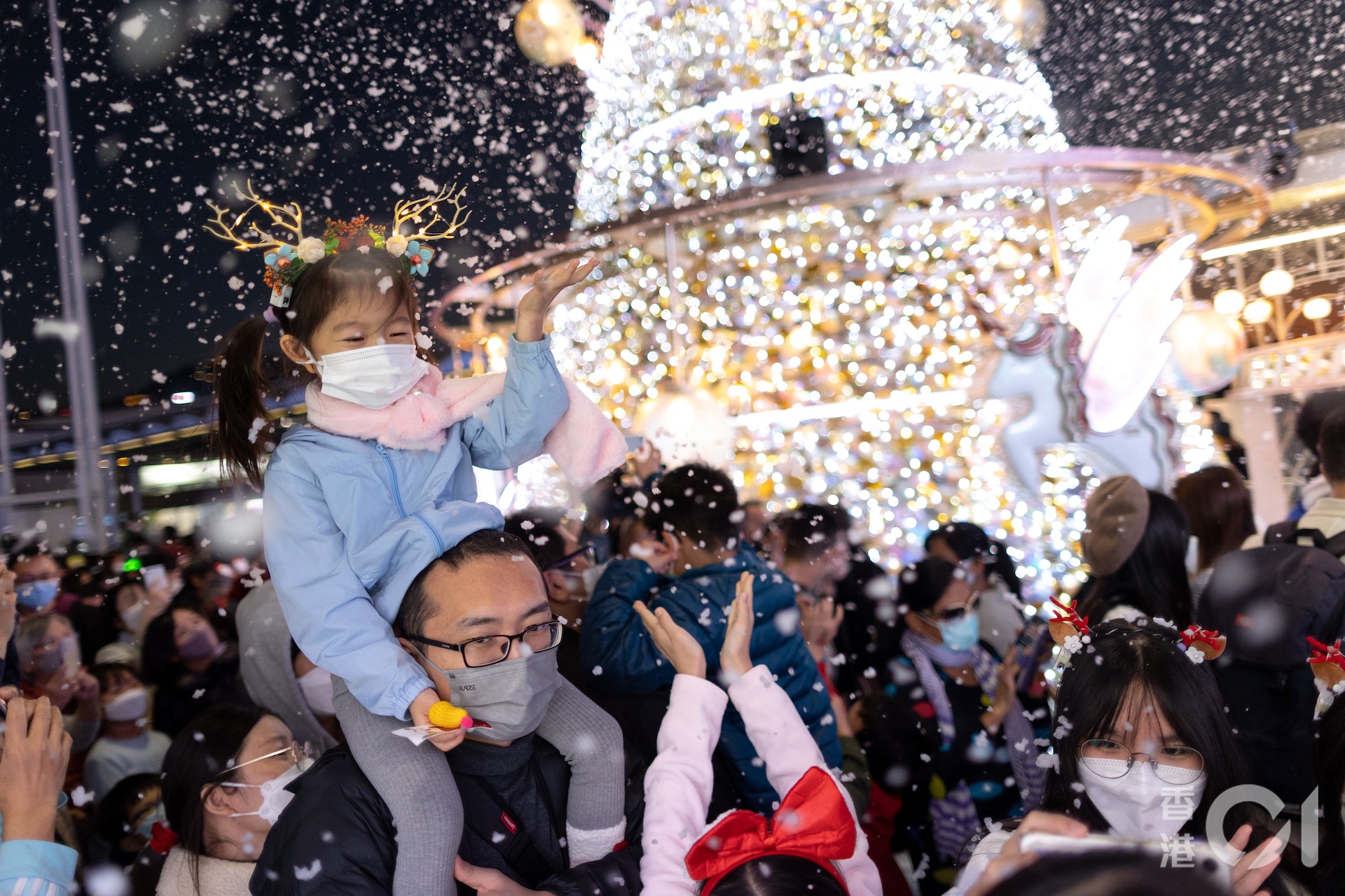 12月24日下平安夜，大批市民到尖沙咀海港城外五支旗桿位置迎聖誕節，商場擺放聖誕樹及定時噴發飄雪，大小朋友都爭着玩樂。（夏家朗攝）