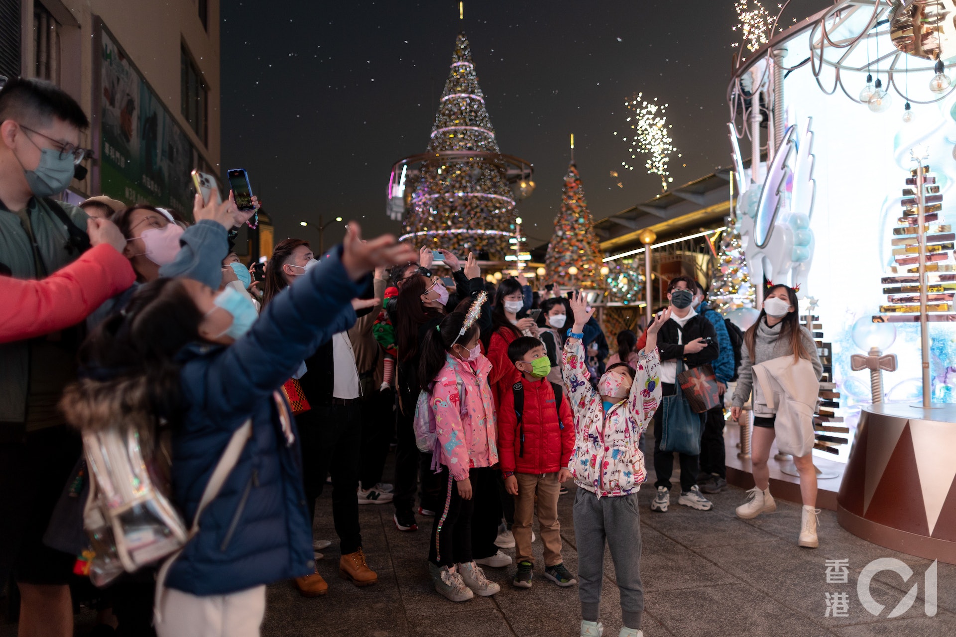 12月24日下平安夜，大批市民到尖沙咀海港城外五支旗桿位置迎聖誕節，商場擺放聖誕樹及定時噴發飄雪，大小朋友都爭着玩樂。（夏家朗攝）