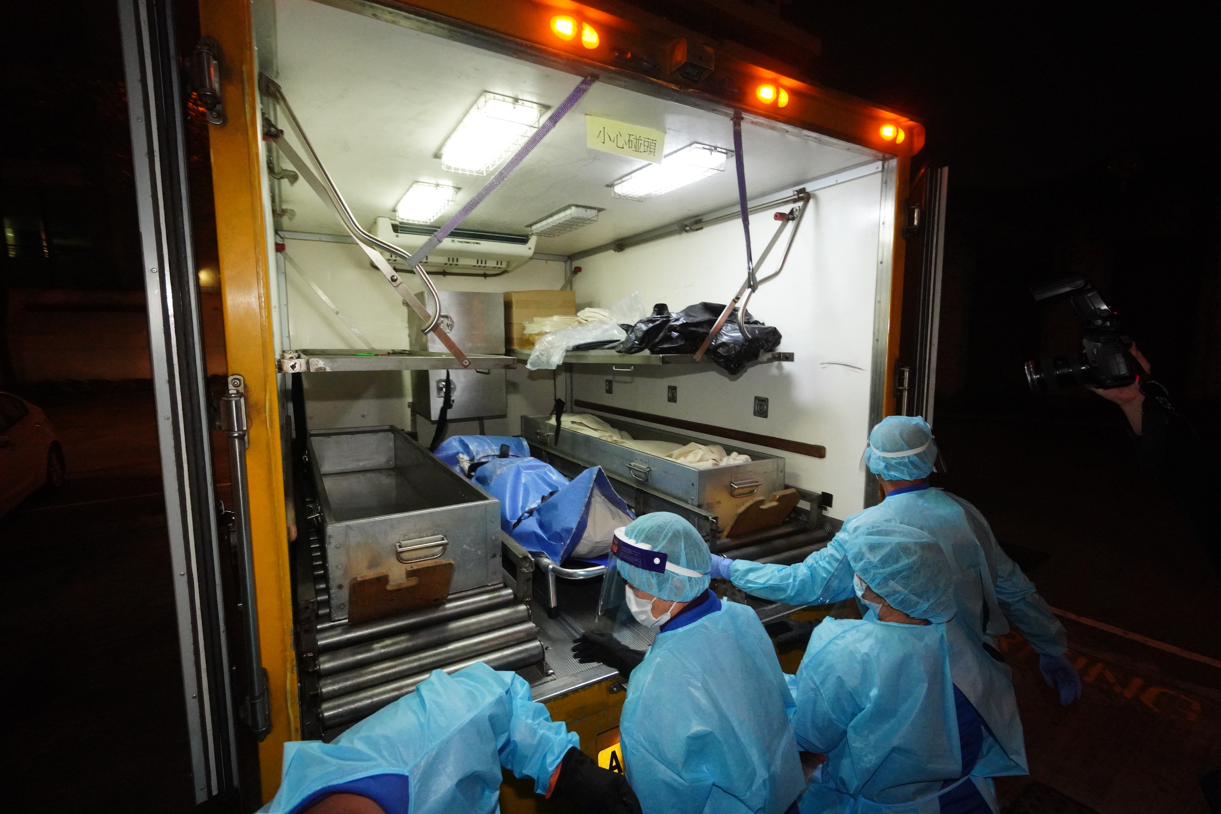 兩具遺體由仵工抬走。（朱永倫攝）