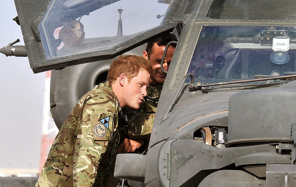 英国王室：图为2012年9月7日，哈里王子于阿富汗的军营与同袍一同检视一部阿帕奇直升机。 王子曾被派驻当地驾驶攻击直升机。 哈里王子在书中称曾夺去25人性命，就像移除棋盘上的棋子一样，引起英国军方以至塔利班政权的不满。 （Getty）