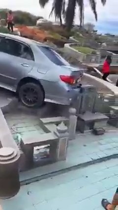 網上瘋傳影片，一輛私家車於狹窄上坡路段倒退時，疑不慎踩油門過猛，竟然向後直衝下坡，壓在下方一墳墓上。（影片截圖）