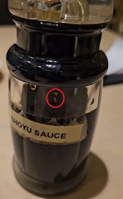 馬來西亞一名男子2023年5月20日在一間日本料理餐廳用餐，之後竟發現桌上醬油瓶內至少有兩條蛆蟲，他向店方反映卻被「冷處理」。圖為影片截圖，可見瓶內蛆蟲（Azrul Razak Facebook賬號）