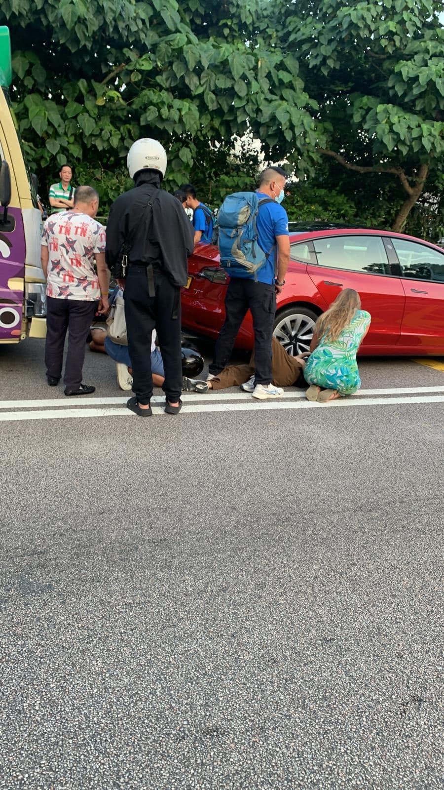 西貢公路三車相撞，見到電單車翻側，現場有兩名男子受傷倒地，途人蹲下視察傷者情況。 （fb群組「車cam L（香港群組）」圖片）