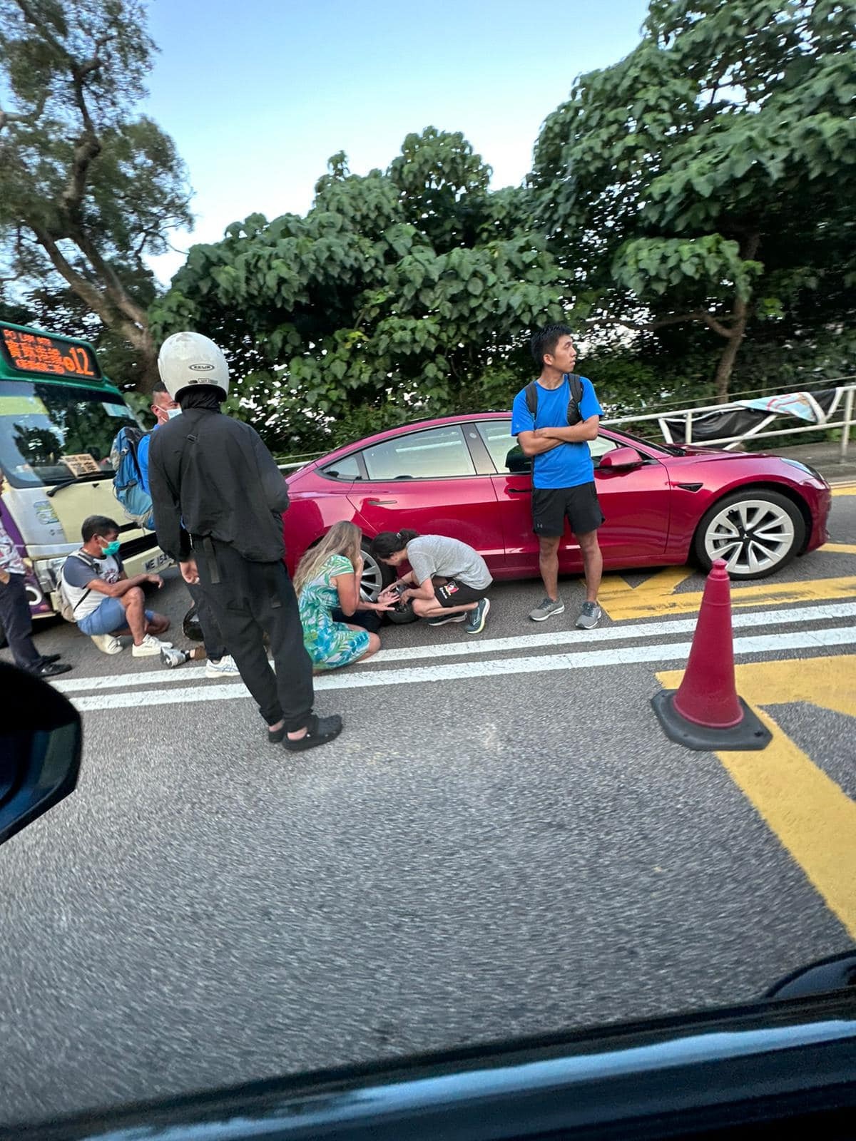 西貢公路三車相撞，見到電單車翻側，現場有兩名男子受傷倒地，途人蹲下視察傷者情況。 （fb群組「車cam L（香港群組）」圖片）