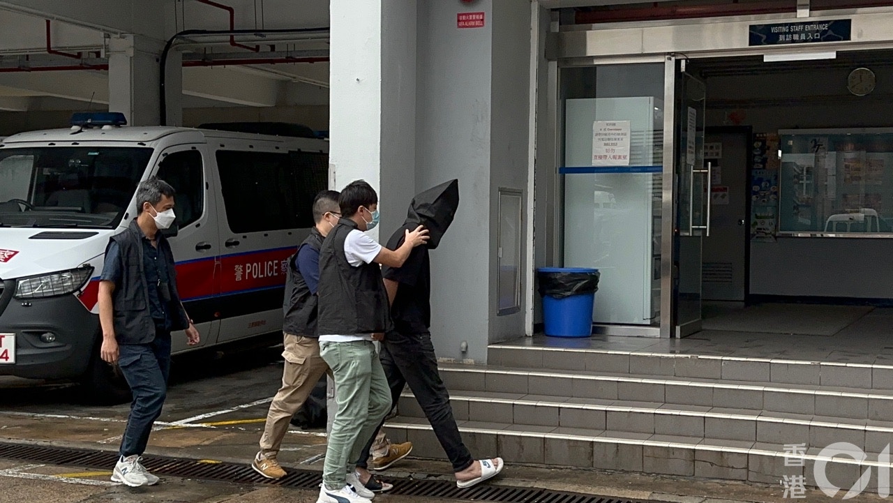 蒙黑色頭套的疑犯被警員押返警署調查。（林澤鋒攝）