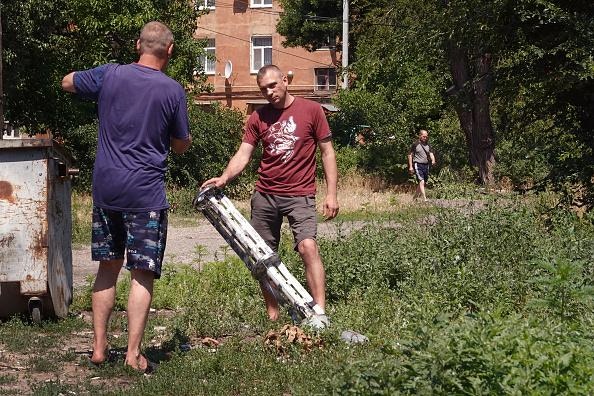烏克蘭局勢：圖為2022年6月27日，一名男子站在烏克蘭斯拉維揚斯克（Sloviansk）住宅區投下集束炸彈的導彈殘骸旁拍照。（Getty）