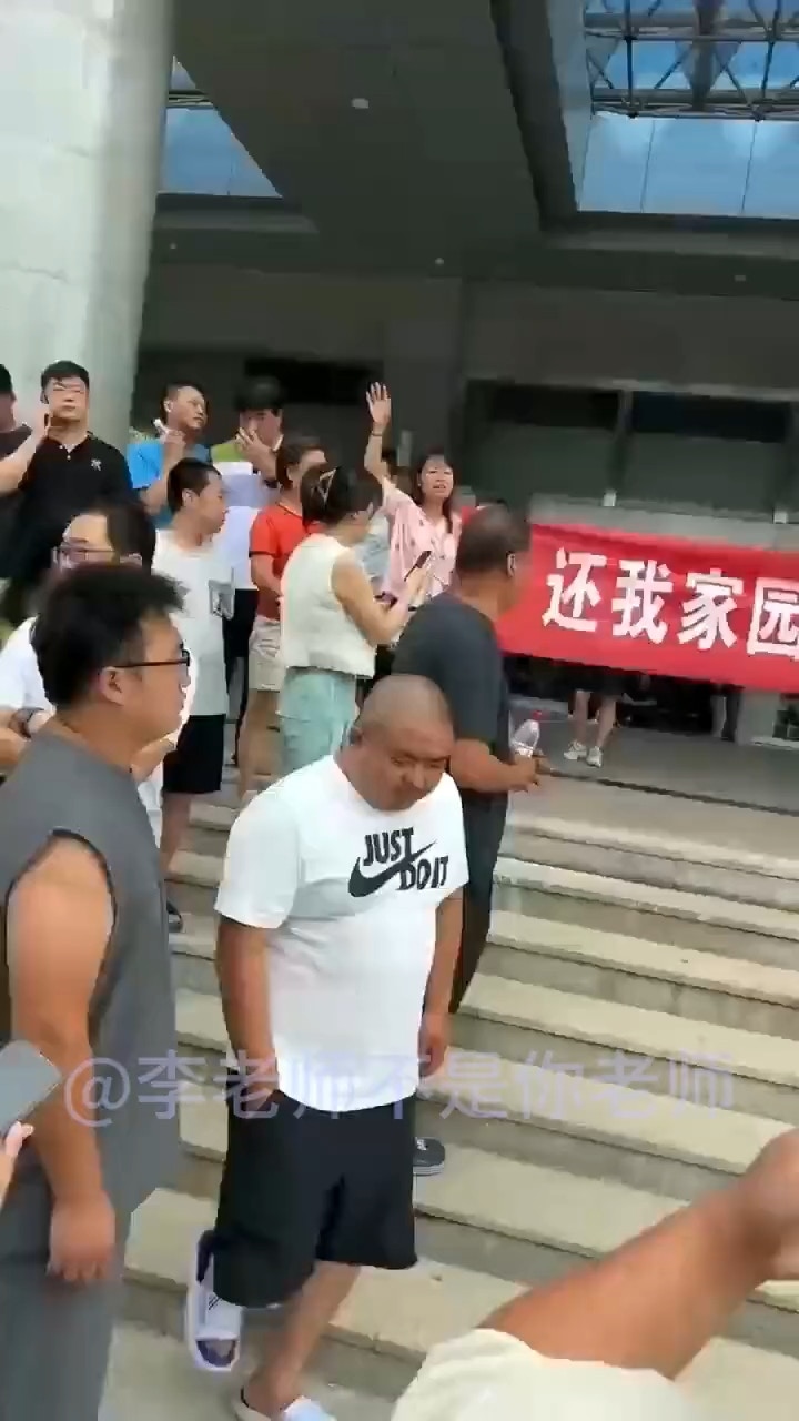 多名霸州市災民4日前往當地政府大樓進行抗議，在現場高舉紅色橫幅布條：「還我家園，明明是泄洪原因，卻說降雨所致」。（影片截圖）