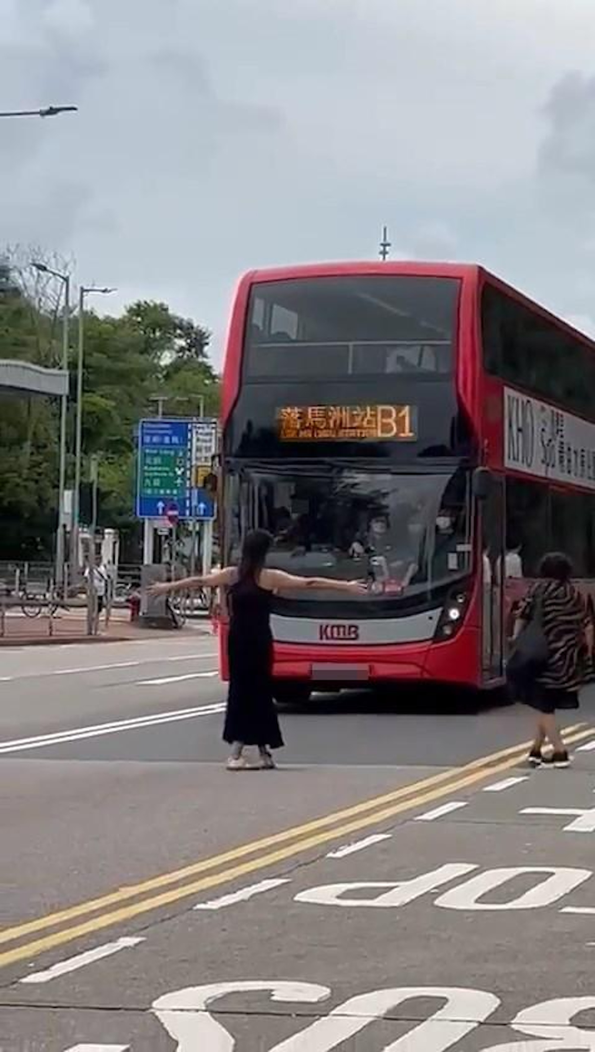 本港網絡下午瘋傳1段影片,只見1名身背心長裙的盛裝女子,疑因上不到往落馬洲B1路線的九巴,竟走到馬路中央用「肉身」擋路,連累巴士停駛。(影片截圖) 本港網絡下午瘋傳1段影片,只見1名身背心長裙的盛裝女子,疑因上不到往落馬洲B1路線的九巴,竟走到馬路中央用「肉身」擋路,連累巴士停駛。(影片截圖)