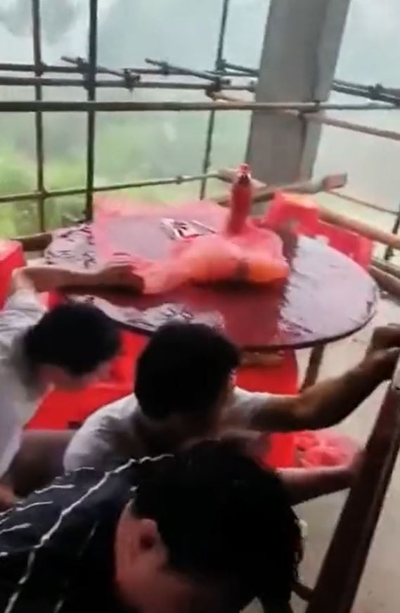 數名男子在爛樓內跪下，就地取材利用木板遮擋風雨。（X影片截圖）