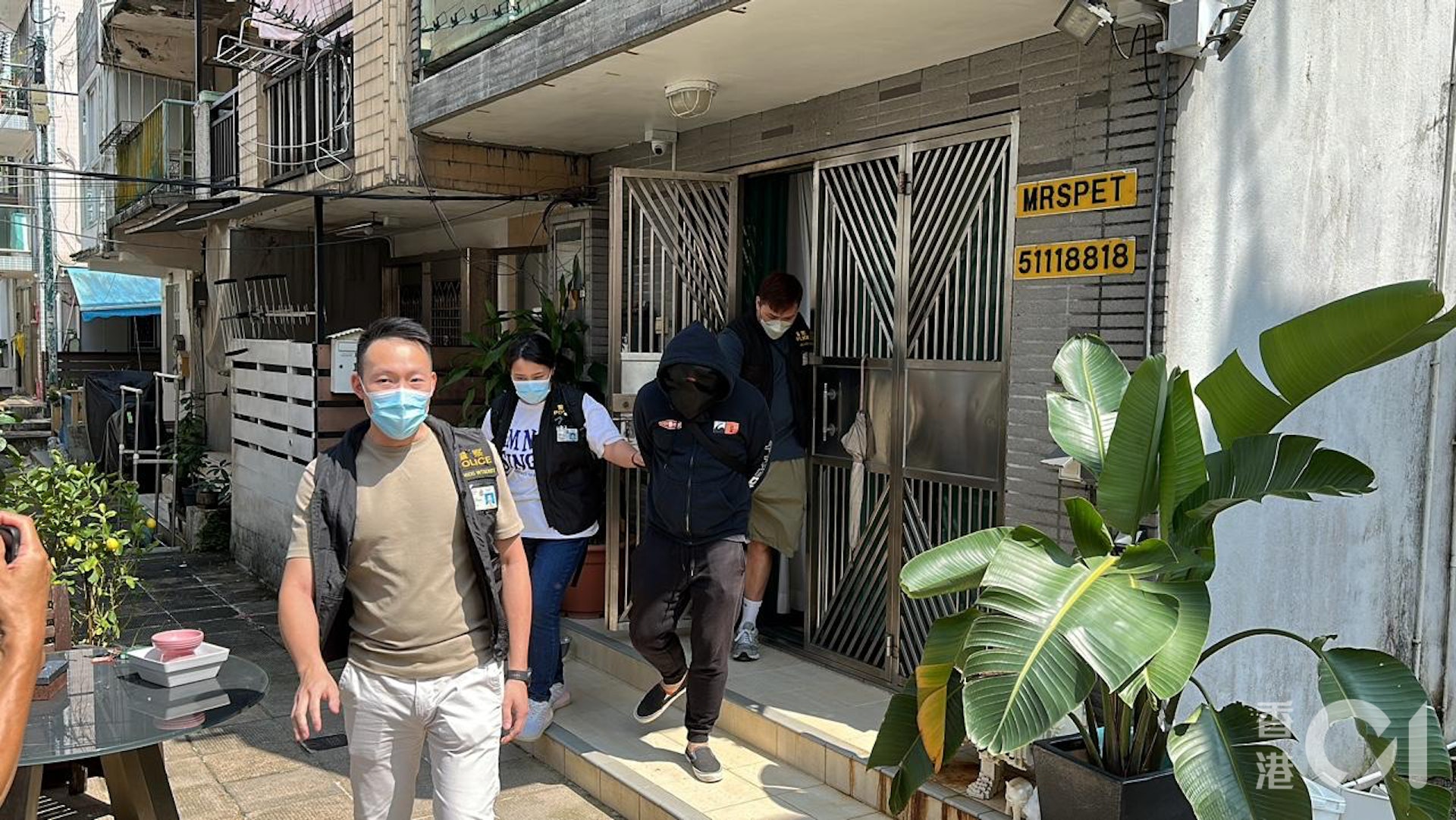 成旭文戴上黑色頭套,在警員押解下步出村屋。(馬耀文攝) 成旭文戴上黑色頭套,在警員押解下步出村屋。(馬耀文攝)