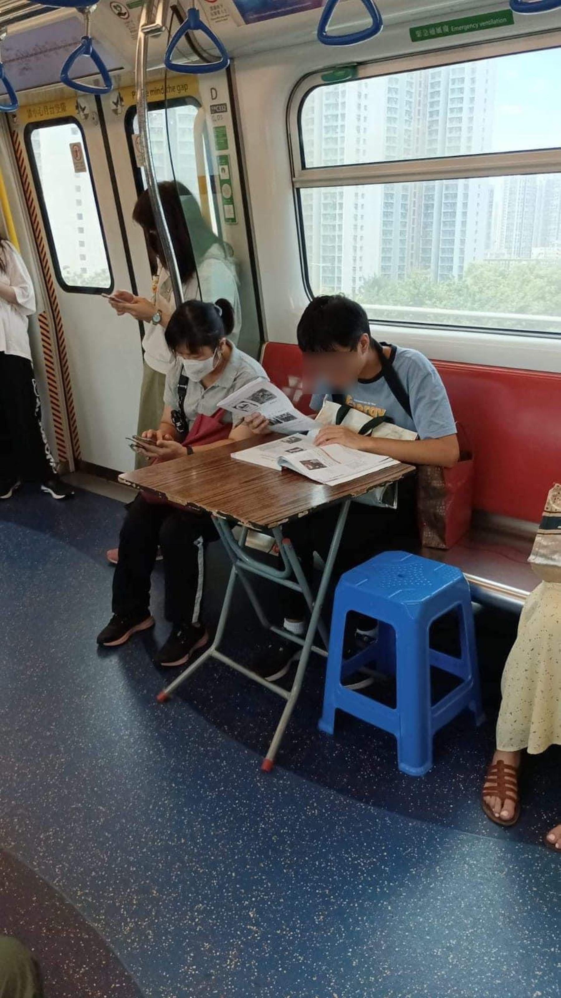 有青年在港鐵車廂內擺放摺枱及膠凳,並在枱上翻閱1本厚書。(連登討論區圖片) 有青年在港鐵車廂內擺放摺枱及膠凳,並在枱上翻閱1本厚書。(連登討論區圖片)