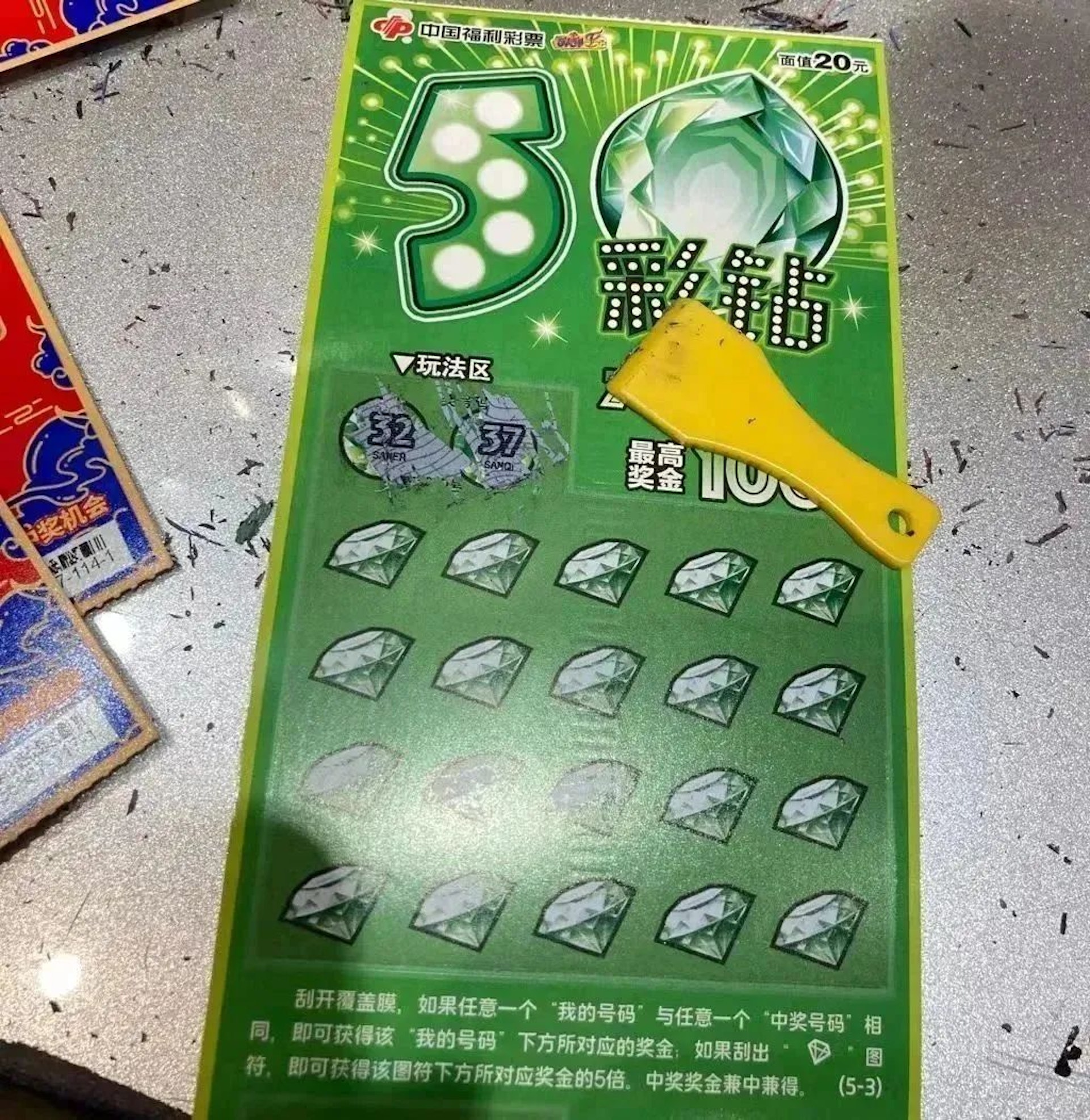 20元面值的五彩鑽,桌面遍佈著其它人刮後留下的油墨屑(深圳微時光授權使用) 20元面值的五彩鑽,桌面遍佈著其它人刮後留下的油墨屑(深圳微時光授權使用)