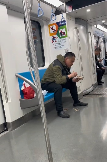 上海地鐵一名男子在車廂內吃魚，更旁若無人地將魚骨吐在地面。（影片截圖）