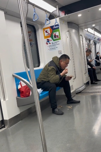 上海地鐵一名男子在車廂內吃魚，更旁若無人地將魚骨吐在地面。（影片截圖）
