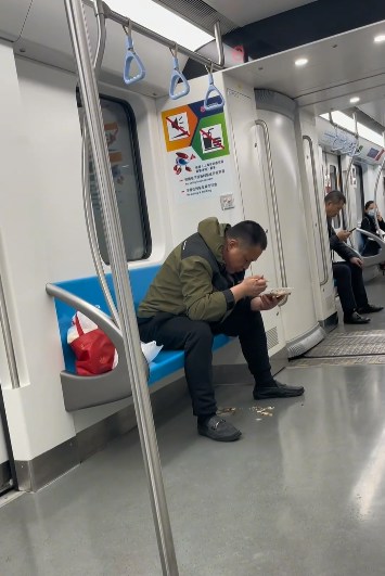 上海地鐵一名男子在車廂內吃魚，更旁若無人地將魚骨吐在地面。（影片截圖）