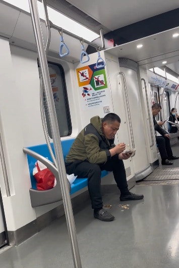 上海地鐵一名男子在車廂內吃魚，更旁若無人地將魚骨吐在地面。（影片截圖）