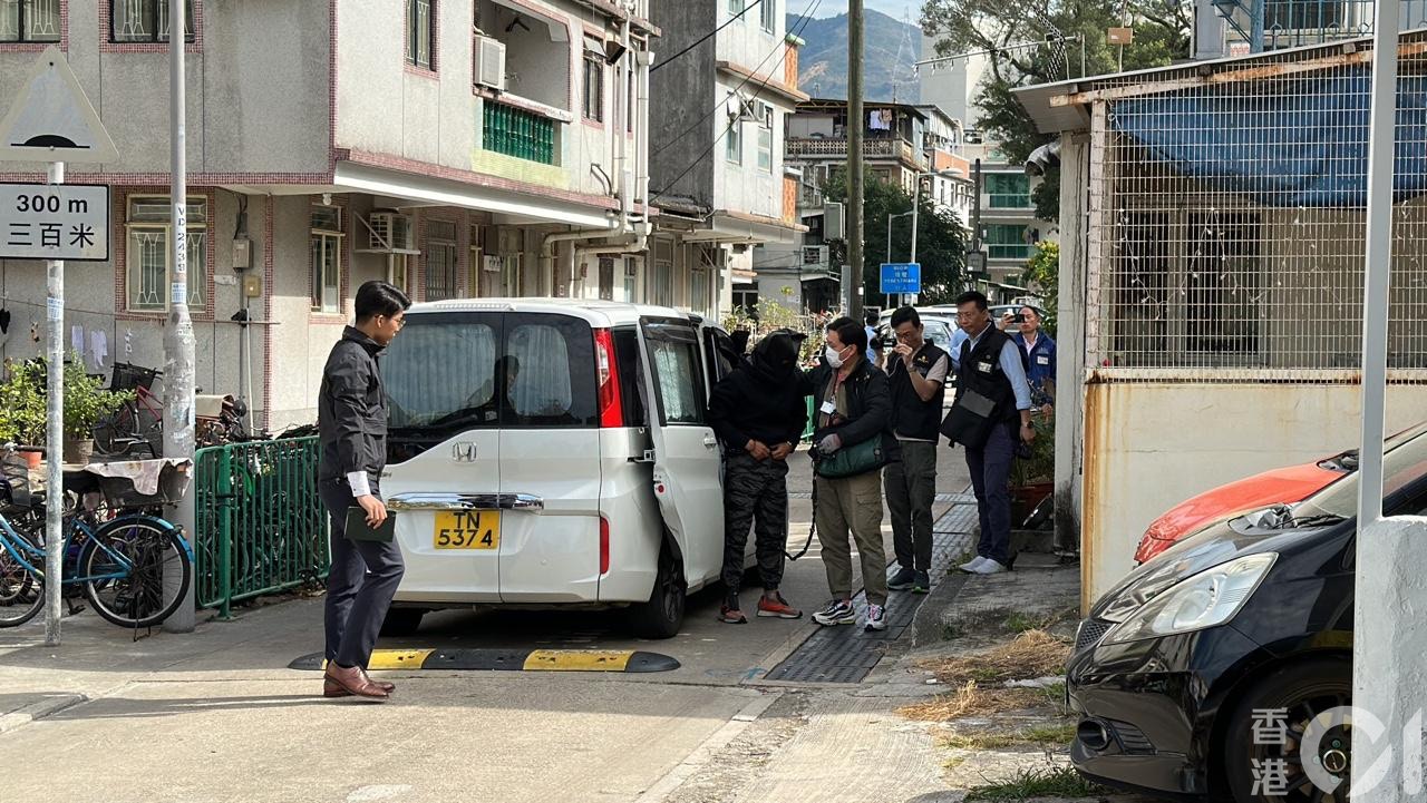 探員將蒙黑色頭套的疑兇帶落車，將他押返村屋重組案情。（馬耀文攝）