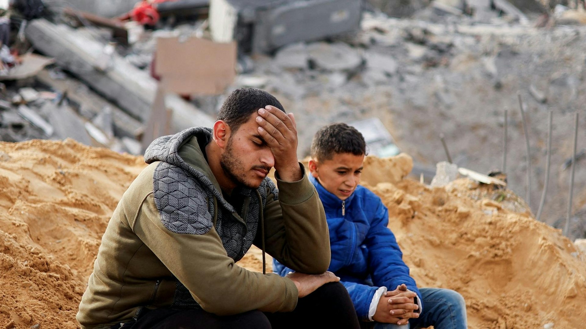 以巴衝突:2024年2月23日,身在加沙走廊南部拉法(Rafah)的巴勒斯坦人在以軍轟炸當地房屋後,頹然坐在襲擊現場附近。(Reuters) 以巴衝突:2024年2月23日,身在加沙走廊南部拉法(Rafah)的巴勒斯坦人在以軍轟炸當地房屋後,頹然坐在襲擊現場附近。(Reuters)